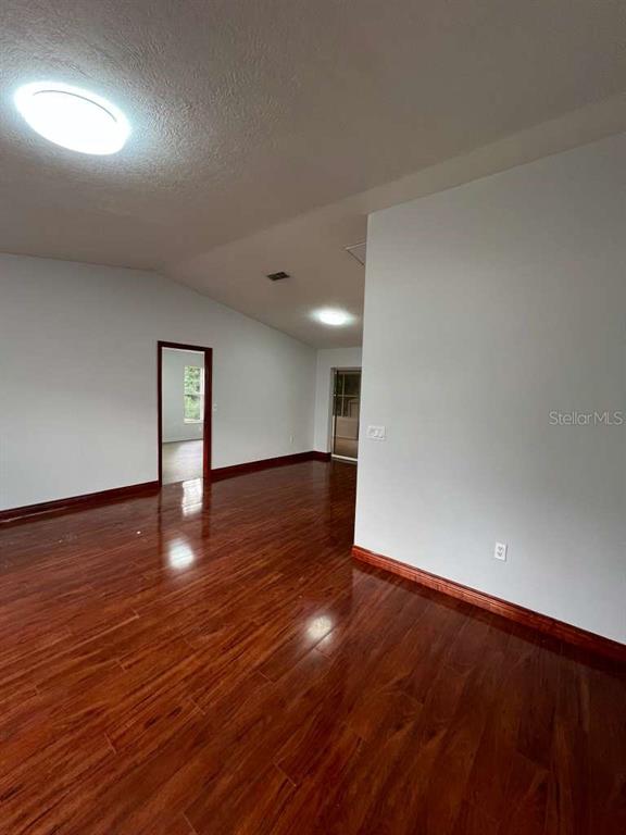 An interior room features light gray walls, dark wood-look flooring, and recessed ceiling lighting — 6206 DORSET ROAD, SPRING HILL, FL