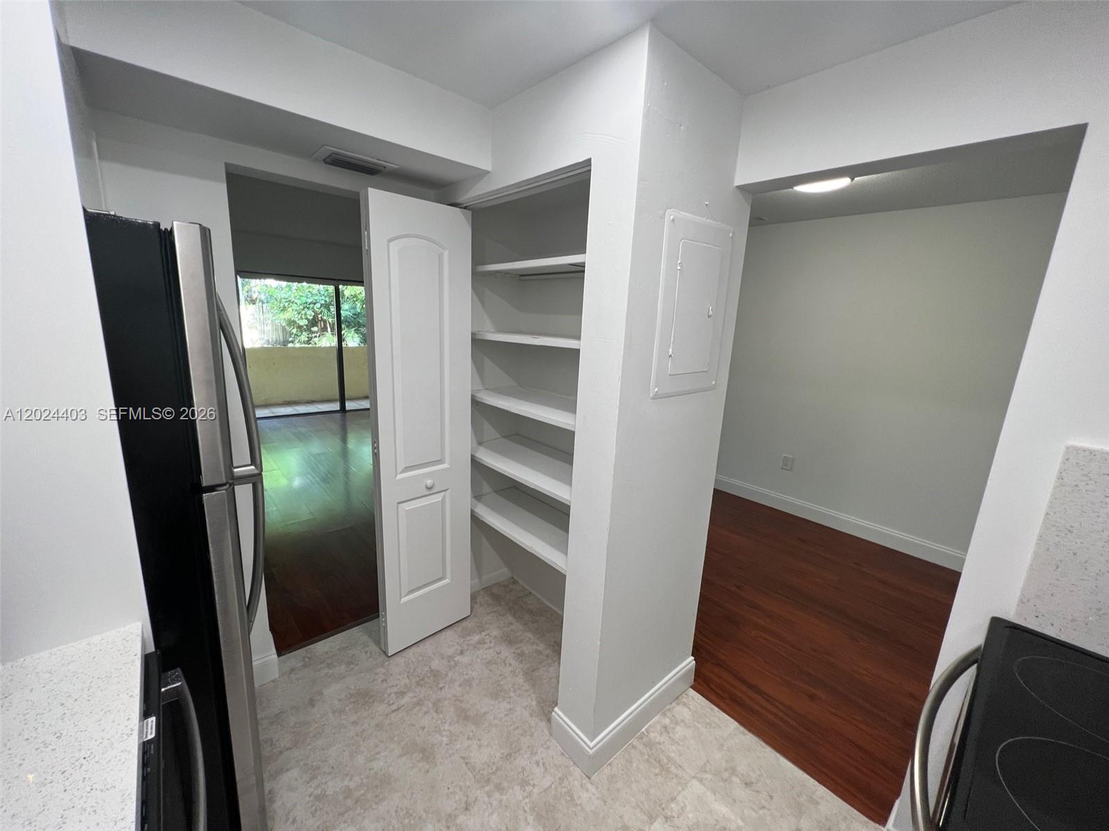 A kitchen area features a pantry with open shelving, stainless steel appliances, and wood flooring — 10415 N Kendall Dr # B113, Miami FL 33176, MIAMI, FL