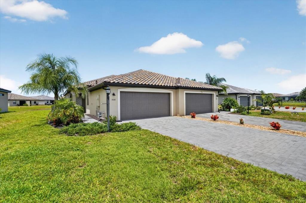 A single-story house with a tiled roof, two garage doors, and a paved driveway — 5316 CRYSTAL HARBOR COVE, BRADENTON, FL