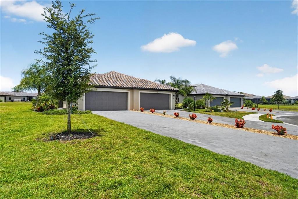 A single-story house with a two-car garage and a paved driveway under a blue sky — 5316 CRYSTAL HARBOR COVE, BRADENTON, FL