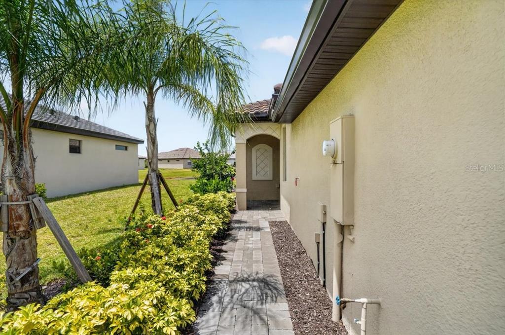 A paved walkway leads along the side of a house past a palm tree — 5316 CRYSTAL HARBOR COVE, BRADENTON, FL