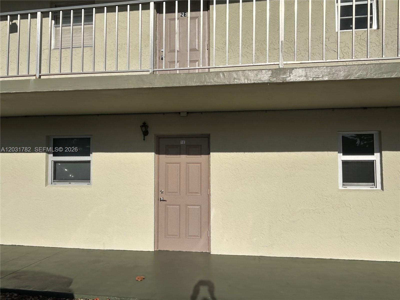 The exterior view shows a ground-floor apartment entrance with a tan door and windows — 609 S State Road 7 # 1E, Margate FL 33068, MARGATE, FL