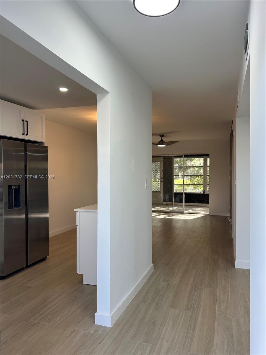 A view from a hallway looking into a kitchen and a living area with tile floors — 609 S State Road 7 # 1E, Margate FL 33068, MARGATE, FL