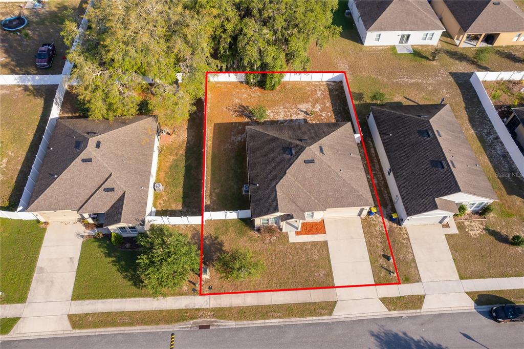 An aerial view shows a single-family home with a fenced backyard outlined in red — 15824 SURFBIRD COURT, MASCOTTE, FL