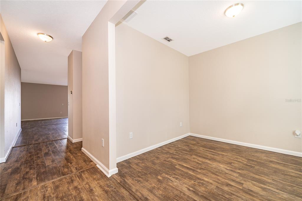 An interior view shows a room with wood-look flooring and beige walls — 15824 SURFBIRD COURT, MASCOTTE, FL