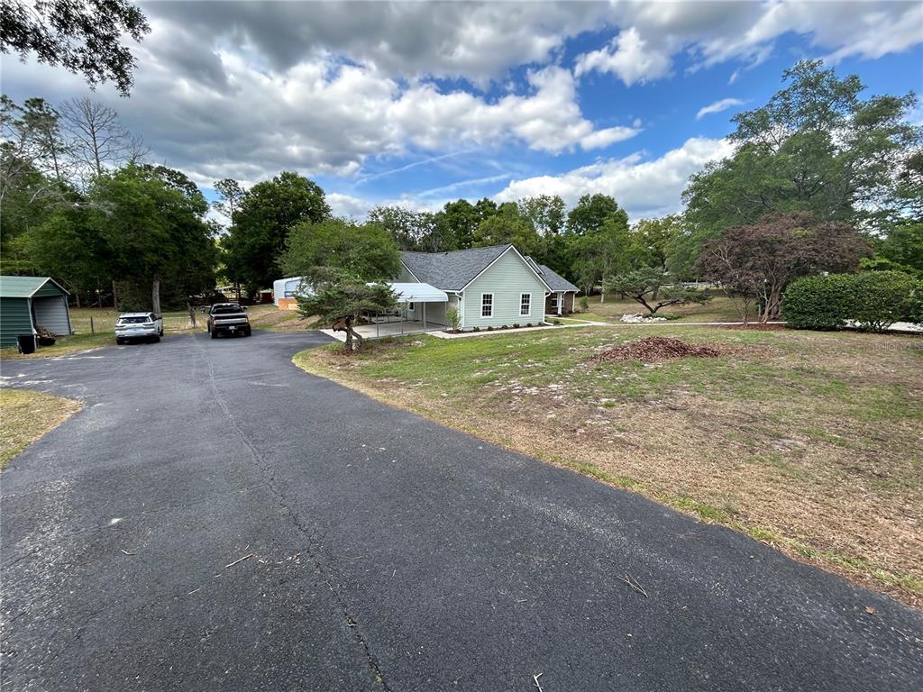 A light green house with a gray roof sits behind a large asphalt driveway — 5340 NE COUNTY ROAD 340, HIGH SPRINGS, FL