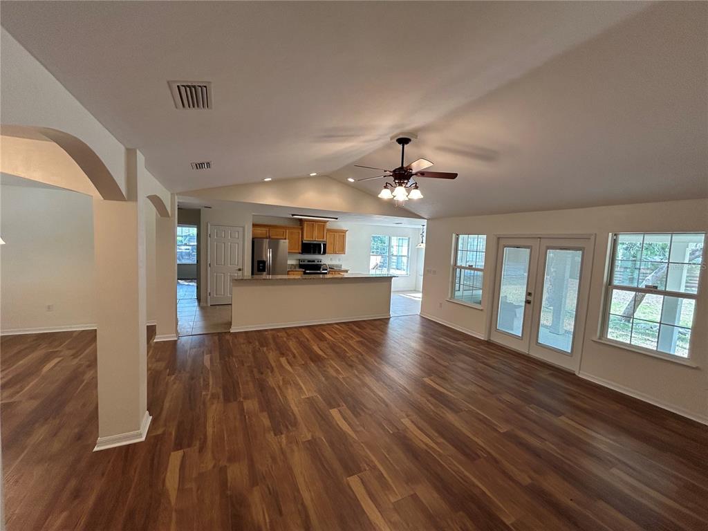 An open-concept living area features wood-look flooring, a vaulted ceiling, and a kitchen with cabinets — 5340 NE COUNTY ROAD 340, HIGH SPRINGS, FL