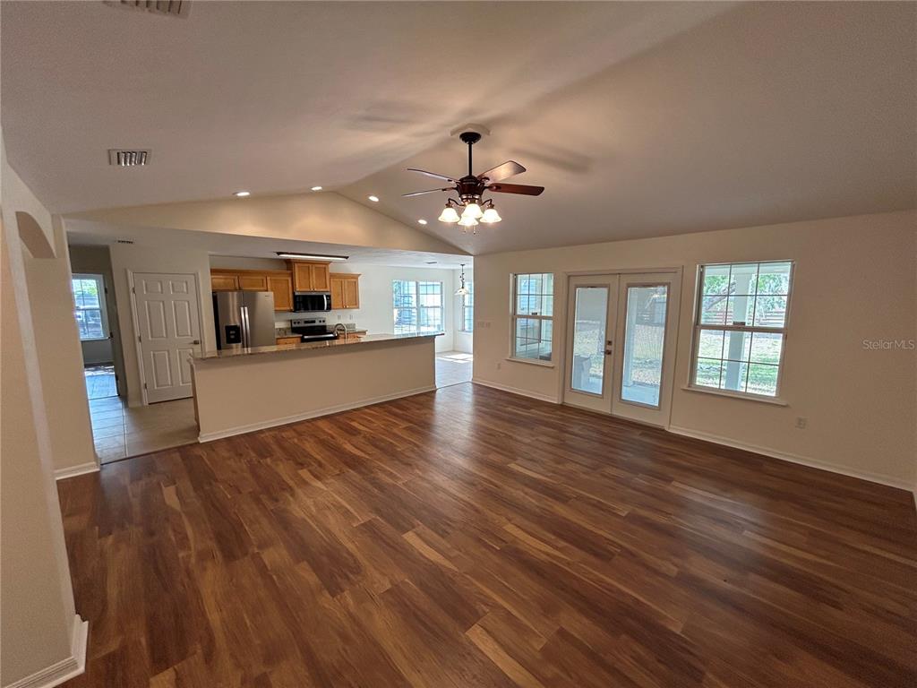 A living room with wood-look flooring, a ceiling fan, and an open kitchen beyond — 5340 NE COUNTY ROAD 340, HIGH SPRINGS, FL