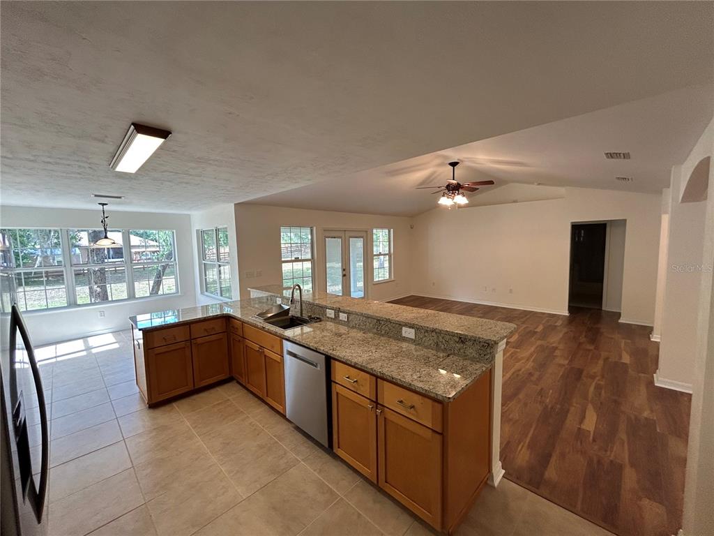 A kitchen with granite countertops and wood cabinets overlooks an open living area with flooring — 5340 NE COUNTY ROAD 340, HIGH SPRINGS, FL