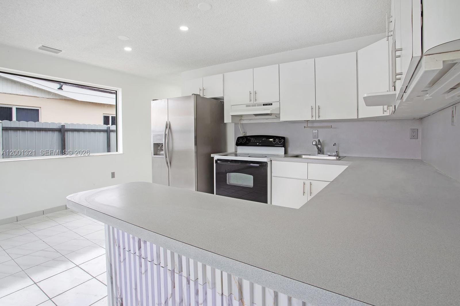 A kitchen features white cabinets, stainless steel appliances, a gray countertop, and a breakfast bar — 11511 SW 180th St, Miami FL 33157, MIAMI, FL