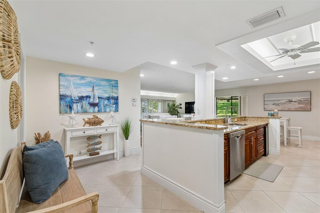 A kitchen with granite countertops and dark wood cabinets opens to a living area — 36750 US HIGHWAY 19 UNIT 21102, PALM HARBOR, FL