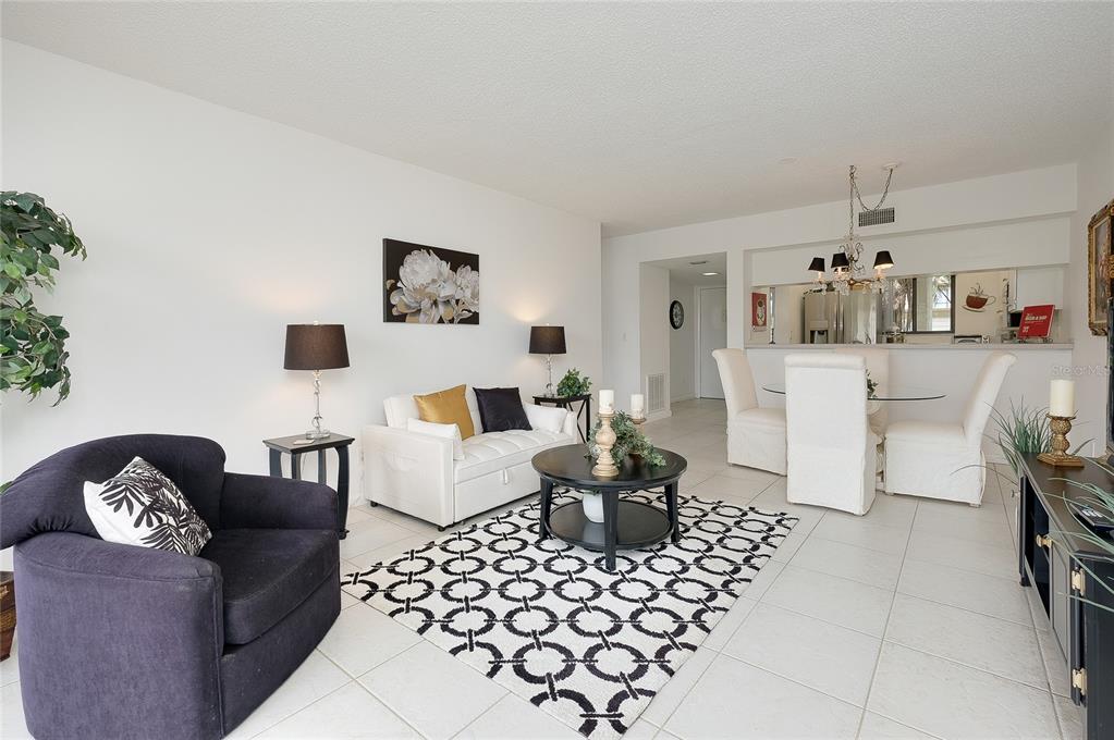 A living and dining area with white tile floors, a black rug, and neutral furniture — 1186 BIRD BAY WAY UNIT 109, VENICE, FL