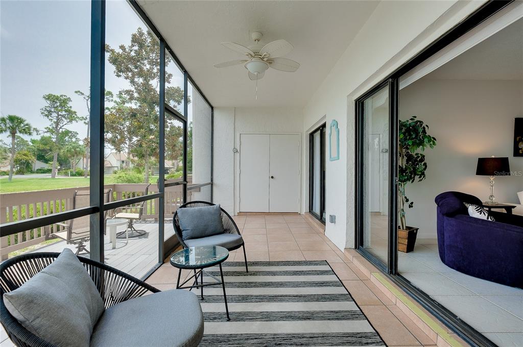 A screened-in porch features tile flooring, a ceiling fan, and views of a grassy area — 1186 BIRD BAY WAY UNIT 109, VENICE, FL