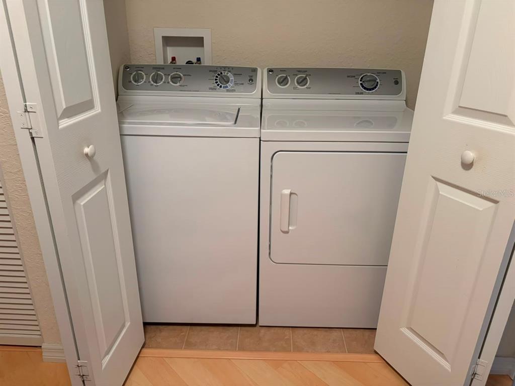 A white top-loading washing machine and dryer are located inside a laundry closet — 4921 NE 123RD LANE, OXFORD, FL