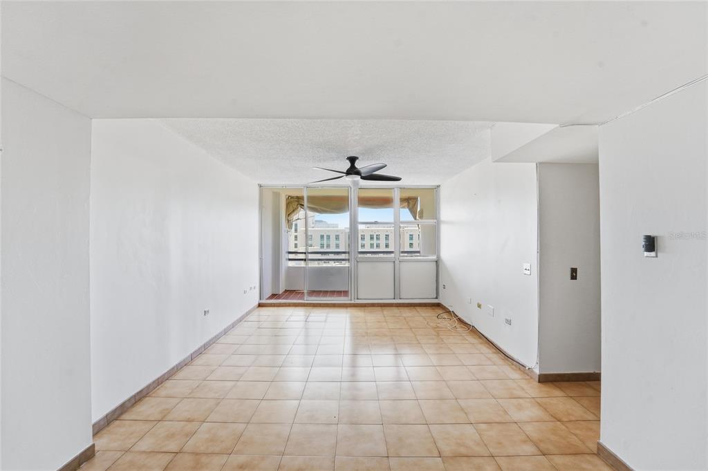 An empty living room features beige tile flooring, white walls, and a sliding glass door — 187 HORIZONTE UNIT 906, CAROLINA, PR