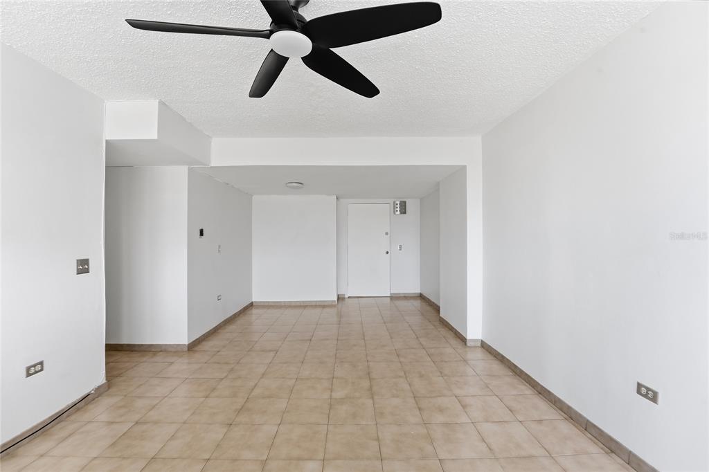 An empty room with white walls, tan tile flooring, and a black ceiling fan — 187 HORIZONTE UNIT 906, CAROLINA, PR