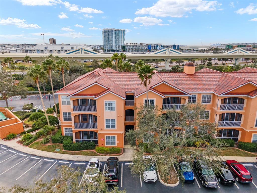 An exterior view of a multi-story orange apartment building with a parking lot in front — 5000 CULBREATH KEY WAY UNIT 4303, TAMPA, FL