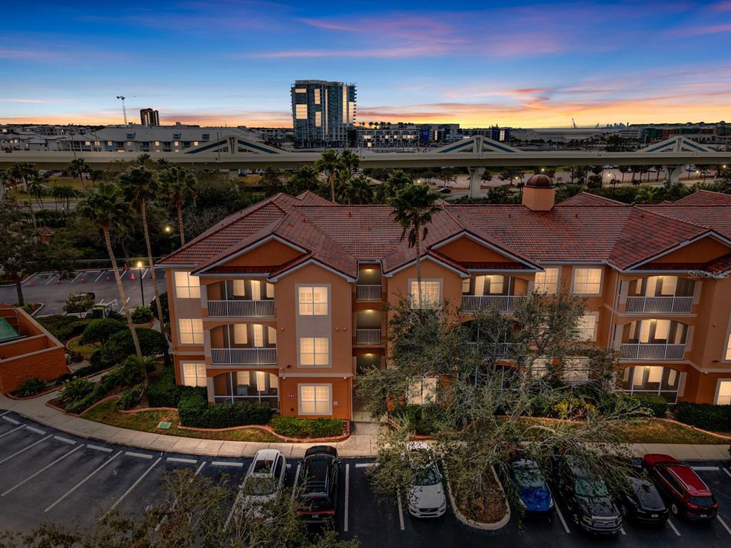 An exterior view of a multi-story apartment building with a parking lot at sunset — 5000 CULBREATH KEY WAY UNIT 4303, TAMPA, FL