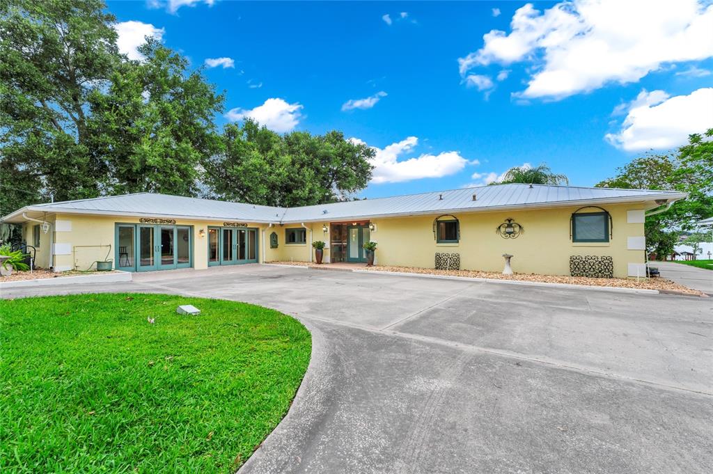 A single-story yellow house with a metal roof sits behind a circular concrete driveway — 6659 LAKE CANE DRIVE, ORLANDO, FL