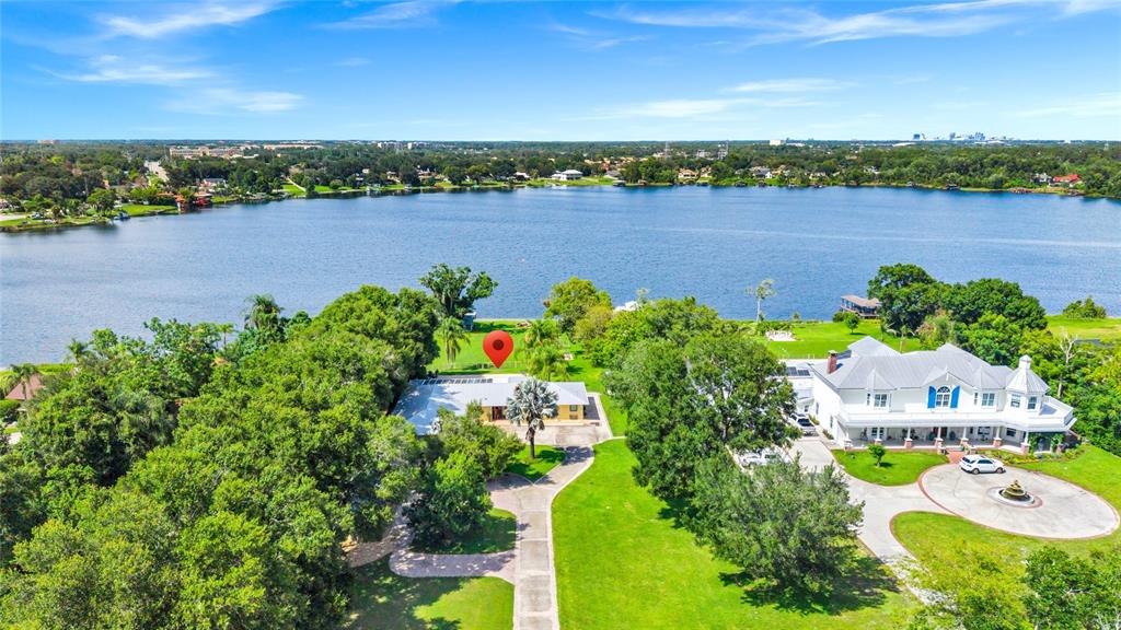 An aerial view shows two houses on a large, grassy lot bordering a lake — 6659 LAKE CANE DRIVE, ORLANDO, FL