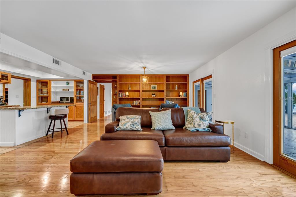 A living room features a brown leather sectional, hardwood floors, and a large wooden bookshelf — 6659 LAKE CANE DRIVE, ORLANDO, FL