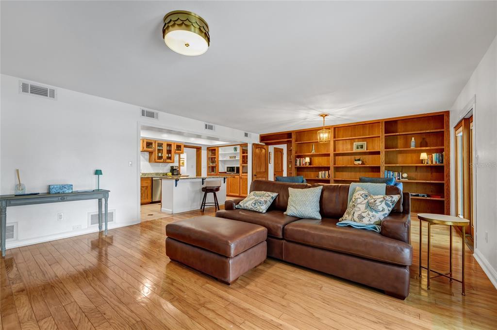 A living room with hardwood floors, a brown leather sofa, and built-in wooden bookshelves — 6659 LAKE CANE DRIVE, ORLANDO, FL
