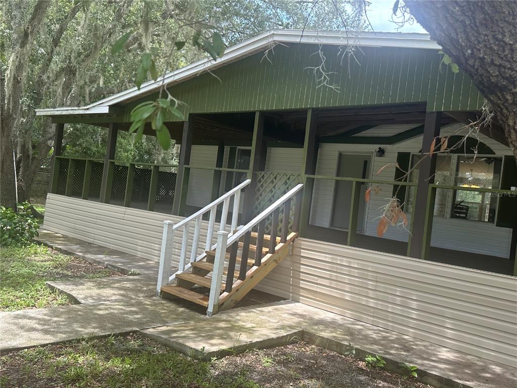 A mobile home exterior features a large screened-in porch with wooden stairs and vinyl siding — 2363 GERBER DAIRY ROAD, WINTER HAVEN, FL