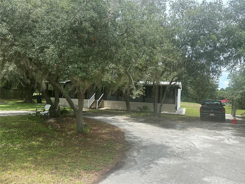 A view from a screened-in porch looking out onto a concrete driveway and trees — 2363 GERBER DAIRY ROAD, WINTER HAVEN, FL