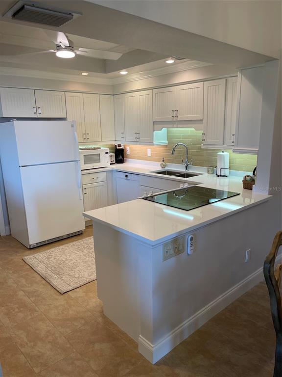 A kitchen features white cabinets, a white refrigerator, a cooktop, and light-colored countertops — 2301 GULF OF MEXICO DRIVE UNIT 11N, LONGBOAT KEY, FL
