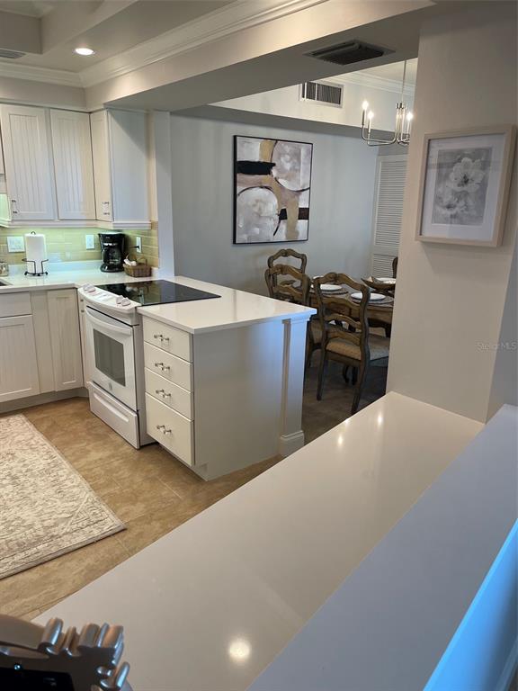 A kitchen with white cabinets and quartz countertops overlooks a dining area with chairs — 2301 GULF OF MEXICO DRIVE UNIT 11N, LONGBOAT KEY, FL