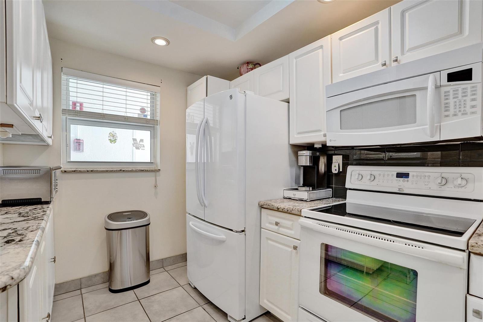 A kitchen with white cabinets, white appliances, granite countertops, and a window with blinds — 1391 S Ocean Boulevard # 309, Pompano Beach FL 33062, POMPANO BEACH, FL