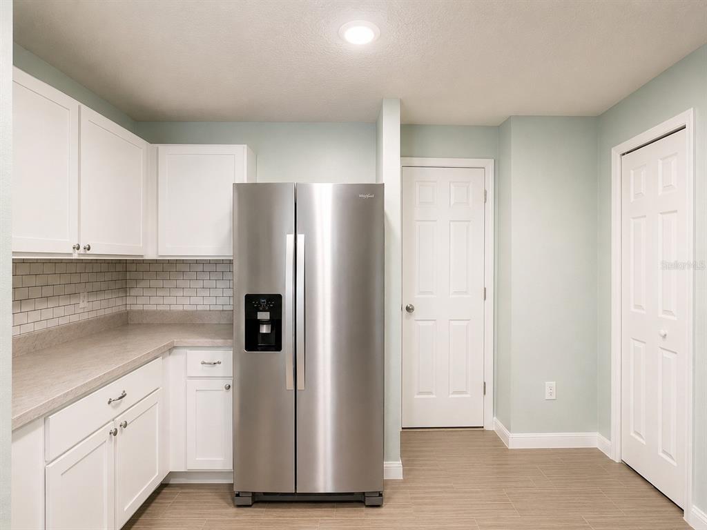 A kitchen featuring white cabinets, a stainless steel refrigerator, and a light-colored tile backsplash — 41 WILLOW LANE, POINCIANA, FL