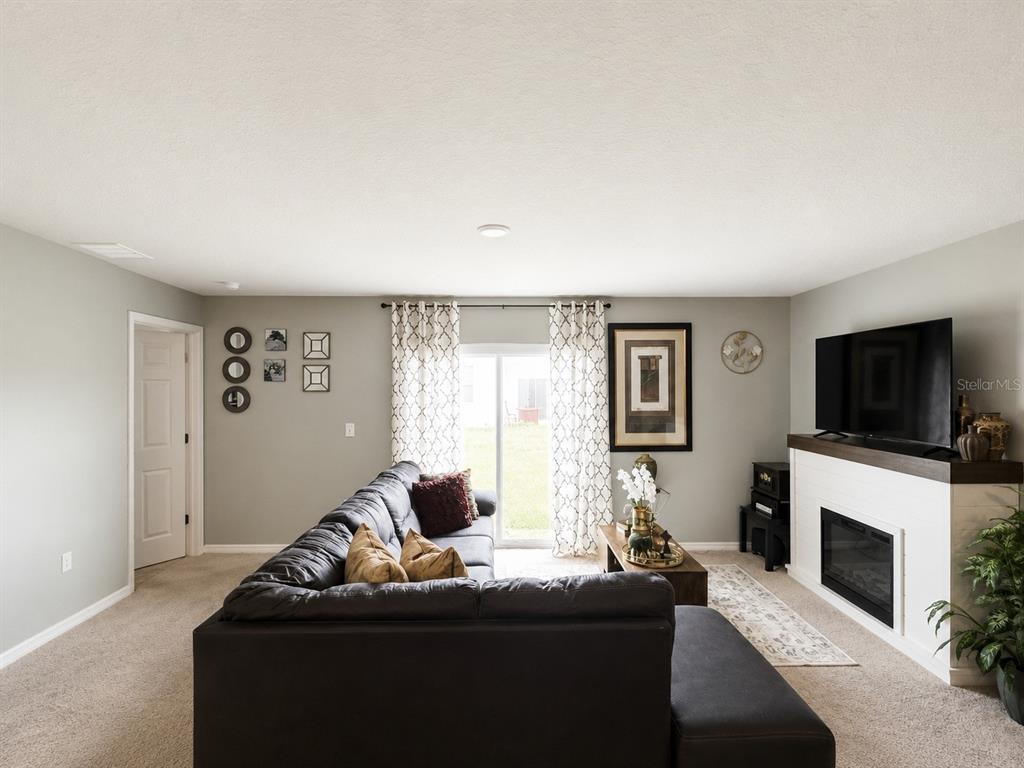 A living room features a dark sectional sofa, a fireplace, and a sliding glass door — 41 WILLOW LANE, POINCIANA, FL
