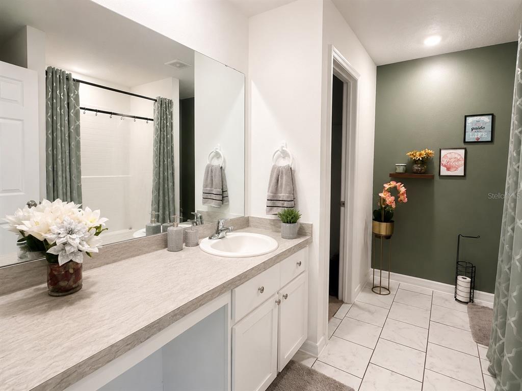 A bathroom features a white vanity with a stone countertop, a mirror, and green walls — 41 WILLOW LANE, POINCIANA, FL