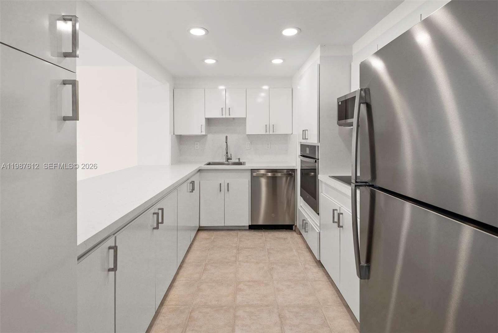 A galley kitchen features white cabinetry, stainless steel appliances, and light-colored countertops — 11111 Biscayne Blvd # 19D, Miami FL 33181, MIAMI, FL