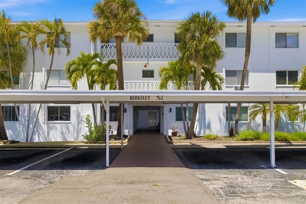A multi-story white apartment building features a covered parking area and a central walkway entrance — 763 JOHN RINGLING BOULEVARD UNIT 22, SARASOTA, FL