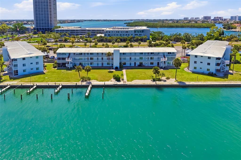 An aerial view of three waterfront apartment buildings with a seawall and boat slips — 763 JOHN RINGLING BOULEVARD UNIT 22, SARASOTA, FL