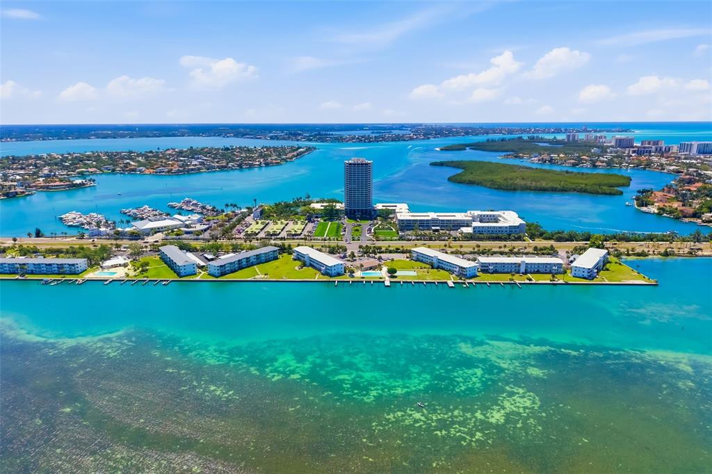 Aerial view of a waterfront condominium complex surrounded by turquoise water and mangrove islands — 763 JOHN RINGLING BOULEVARD UNIT 22, SARASOTA, FL