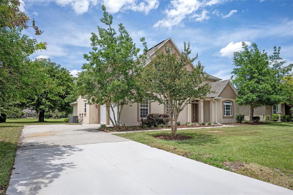 A two-story house with a concrete driveway, tan siding, and mature trees in the front yard — 265 MOSES CREEK BOULEVARD, ST AUGUSTINE, FL
