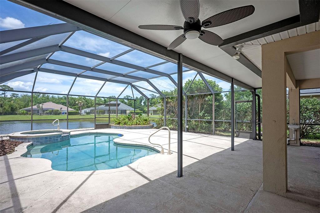 A screened-in patio features a swimming pool, a hot tub, and a ceiling fan — 265 MOSES CREEK BOULEVARD, ST AUGUSTINE, FL
