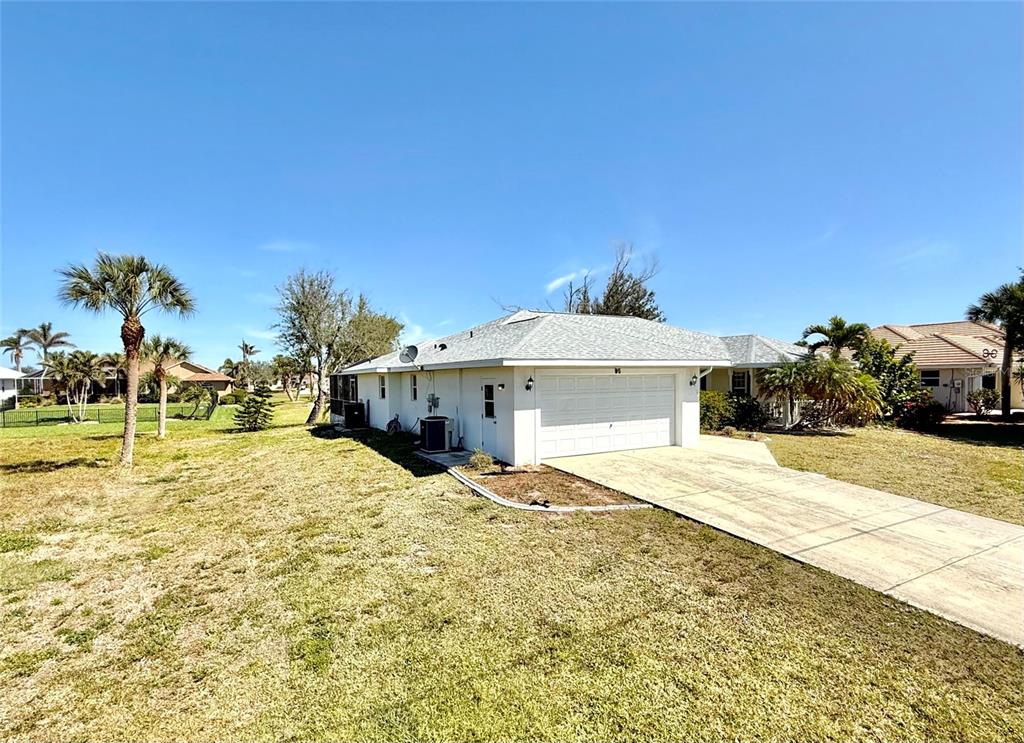 A white single-story house features a two-car garage, a concrete driveway, and palm trees — 95 WHITE MARSH LANE, ROTONDA WEST, FL