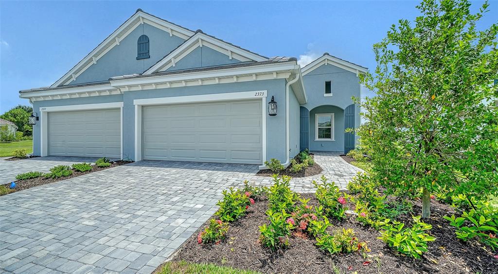 A light blue house with a paved driveway and a landscaped front yard — 2373 BLUE MAHOE LANE, SARASOTA, FL