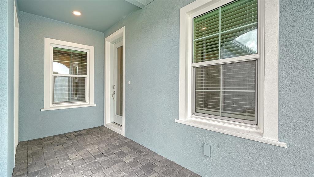 A covered porch with light blue stucco walls, a paver floor, and two windows — 2373 BLUE MAHOE LANE, SARASOTA, FL