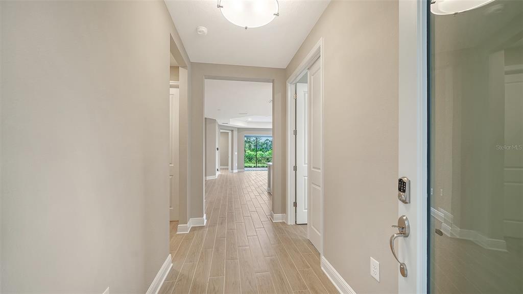 A brightly lit foyer leads into a hallway with light-colored tile flooring and white doors — 2373 BLUE MAHOE LANE, SARASOTA, FL