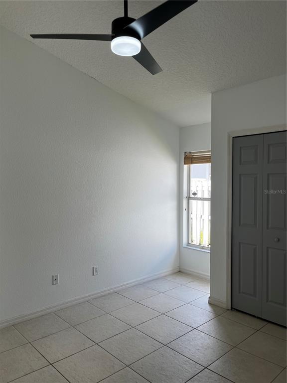 A bedroom features white walls, tile flooring, a ceiling fan, and a gray closet door — 5007 TERRA VISTA WAY, ORLANDO, FL