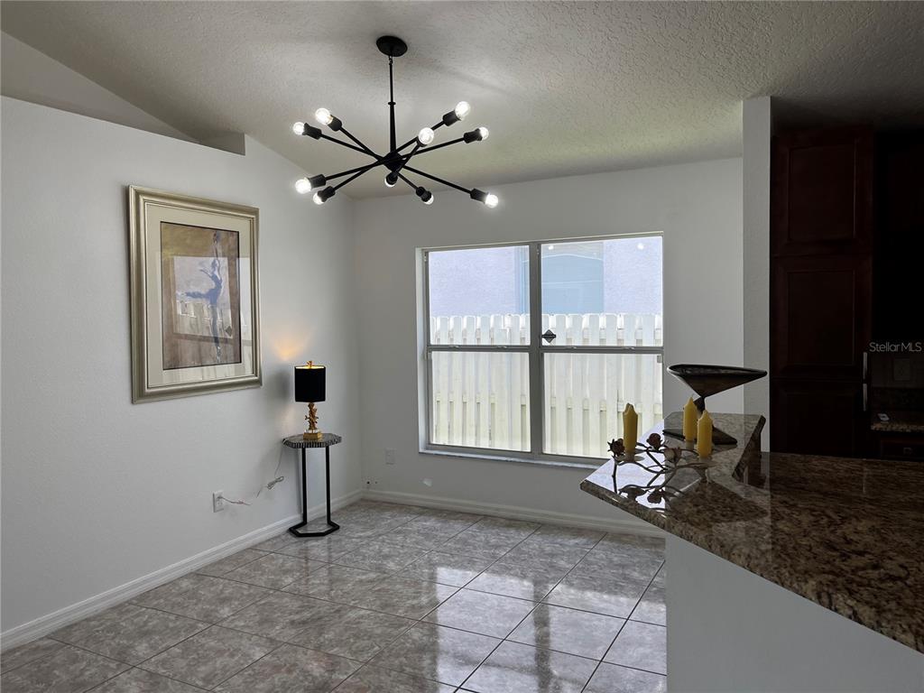 A dining area features tile flooring, a modern chandelier, and a window overlooking a fence — 5007 TERRA VISTA WAY, ORLANDO, FL