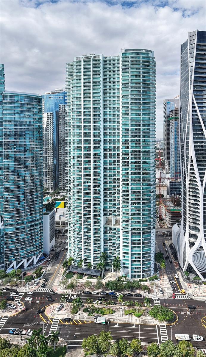 An aerial view shows a tall, modern glass residential skyscraper surrounded by other high-rise buildings — 900 BISCAYNE BLVD # 909, Miami FL 33132, MIAMI, FL
