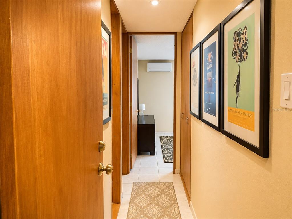 A hallway with framed posters on the wall leads to a room with a dresser — 1035 AVE. ASHFORD UNIT 407, SAN JUAN, PR