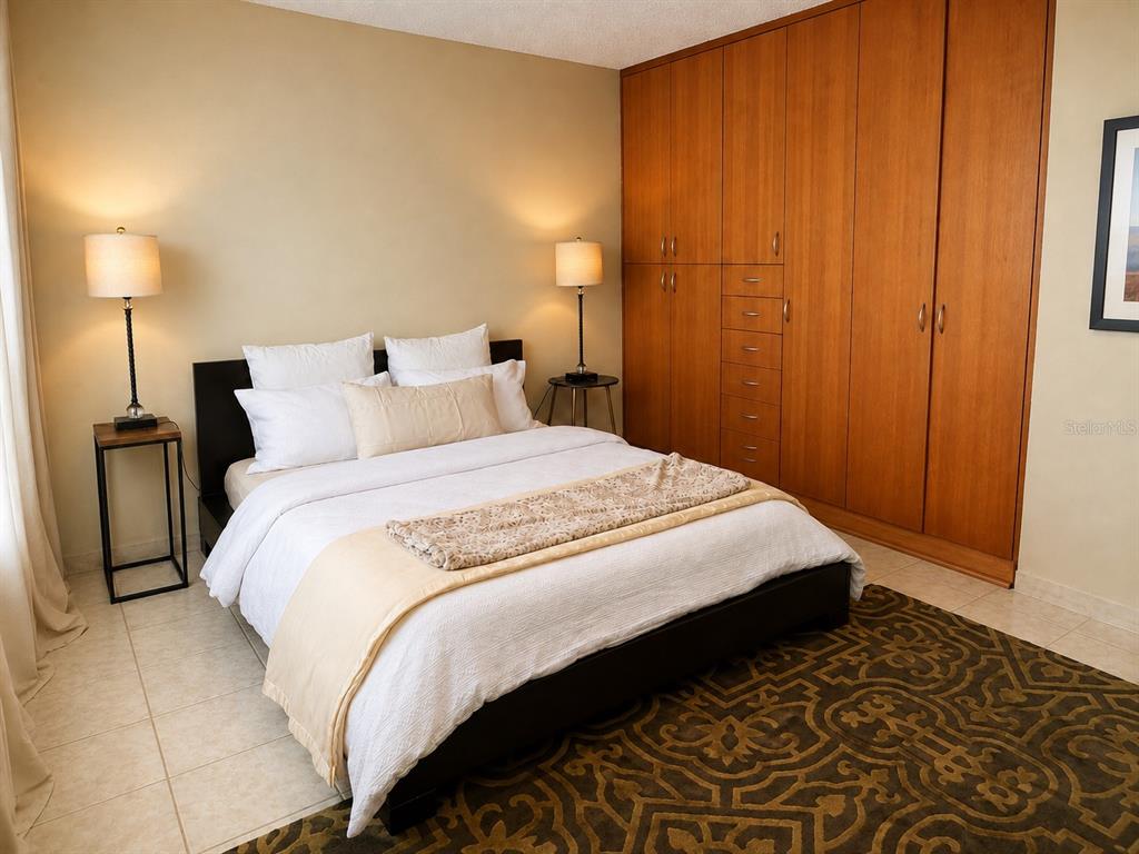A bedroom features a bed with white bedding, two side tables, and a large wooden wardrobe — 1035 AVE. ASHFORD UNIT 407, SAN JUAN, PR