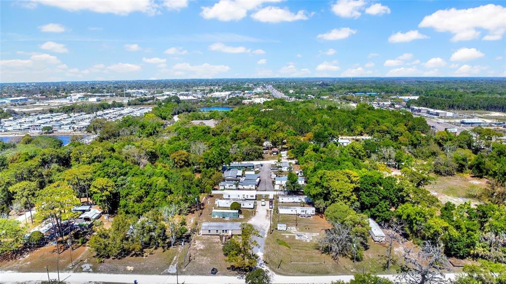 An aerial view shows a mobile home park surrounded by dense trees and nearby roads — 8325 EMMONS AVENUE, NEW PORT RICHEY, FL